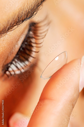 Fotografie Woman putting contact lens in her eye