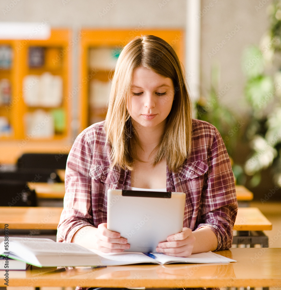 Teenage girl using electronic tablet at library Teenage girl using electronic tablet at library
