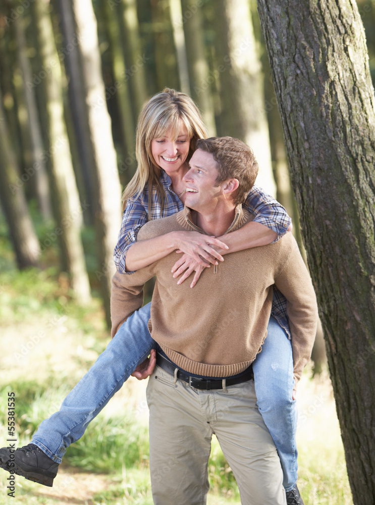 Man Giving Woman Piggyback On Country Walk