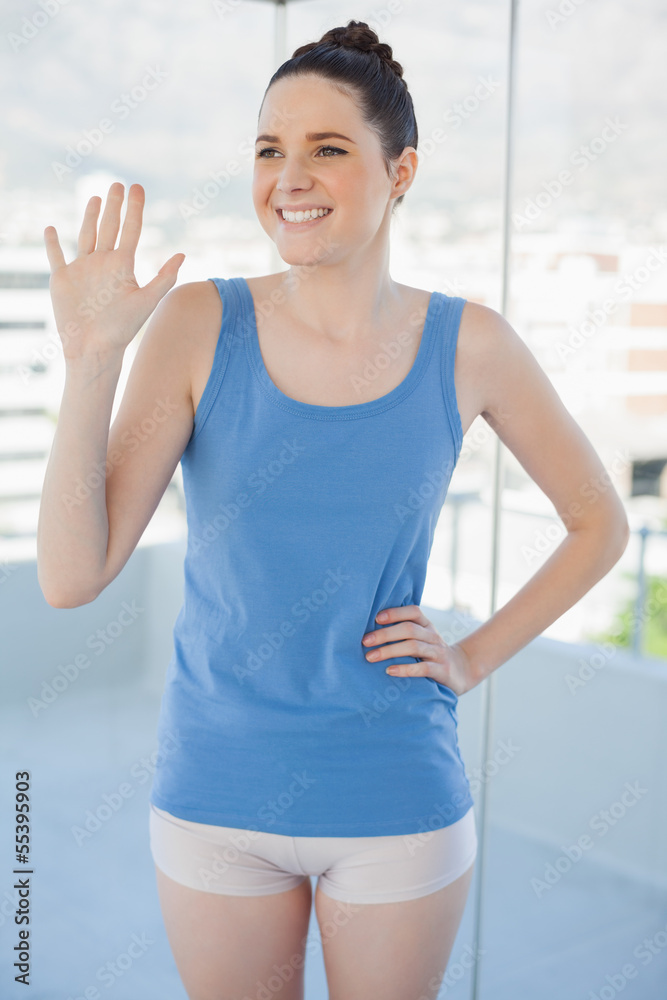 Smiling slender woman in sportswear waving Smiling slender woman in sportswear waving