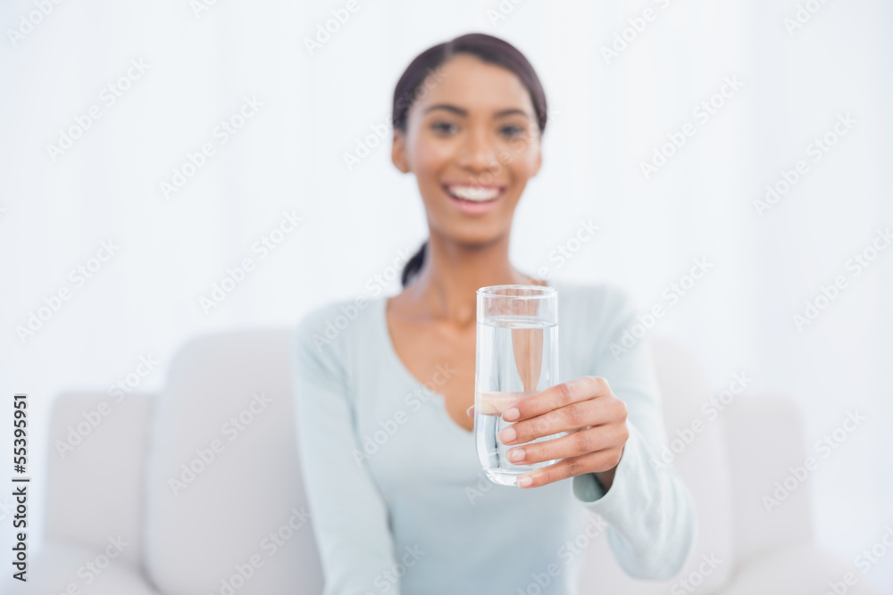 Smiling attractive woman sitting on cosy sofa holding glass of w Smiling attractive woman sitting on cosy sofa holding glass of w