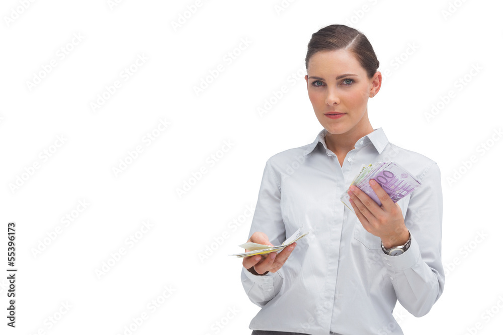 Businesswoman holding wads of cash and looking at camera Businesswoman holding wads of cash and looking at camera
