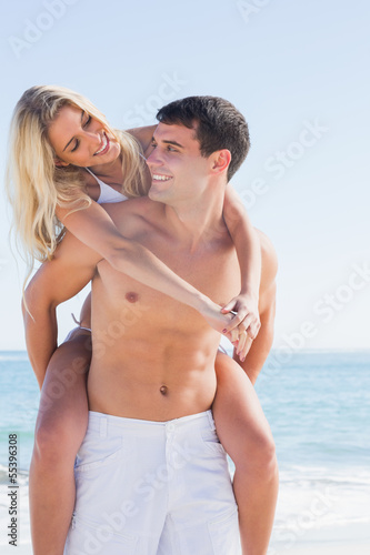 Happy man giving his pretty girlfriend a piggy back