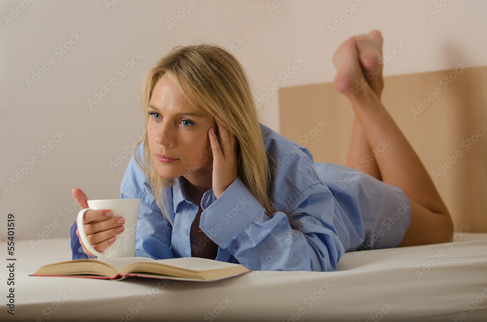 young beautiful woman is reading a book and drinking coffee young beautiful woman is reading a book and drinking coffee