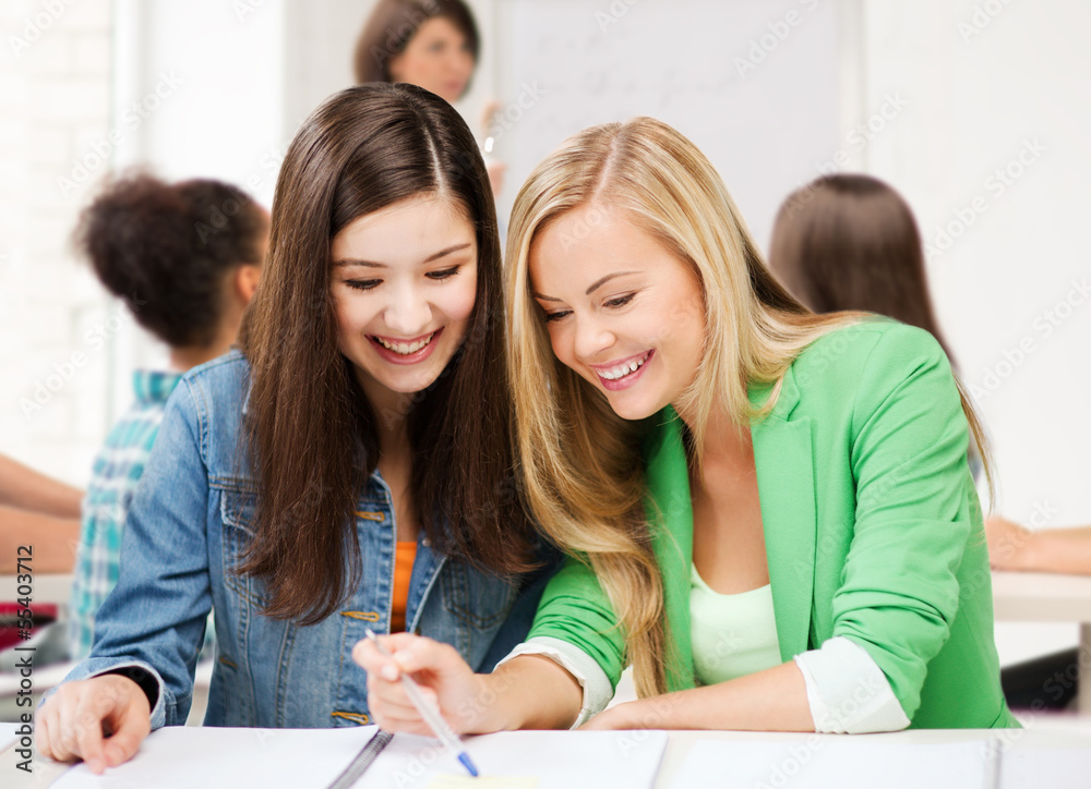 student girls pointing at notebook at school student girls pointing at notebook at school