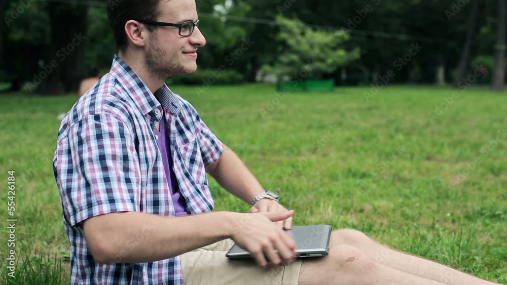 Relaxing young student with laptop in the park