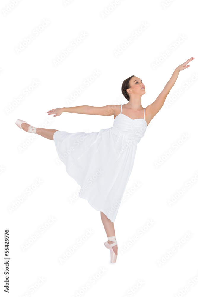 Focused ballet dancer posing on her tiptoe while rising a leg Focused ballet dancer posing on her tiptoe while rising a leg