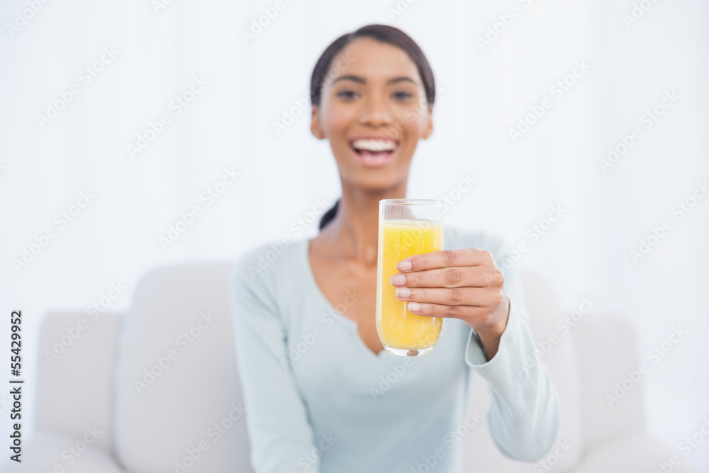 Smiling woman sitting on cosy sofa holding glass of orange juice Smiling woman sitting on cosy sofa holding glass of orange juice