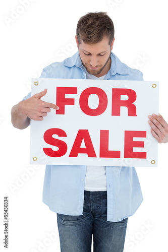 Trendy model holding a for sale sign and looking at it