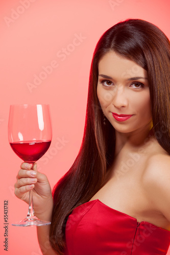 Woman with glass of wine. Beautiful young woman in red dress hol