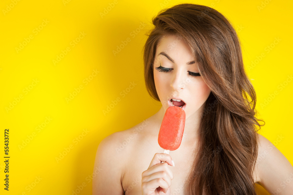 Young girl eating ice cream against yellow background. Young girl eating ice cream against yellow background.