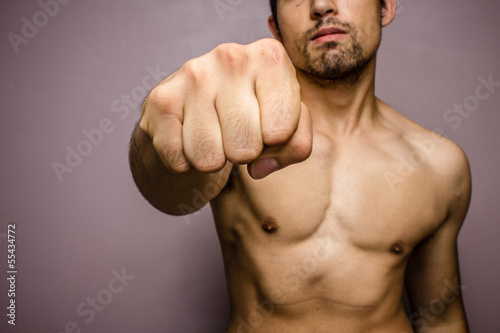 Young man with muscular physique punching photo