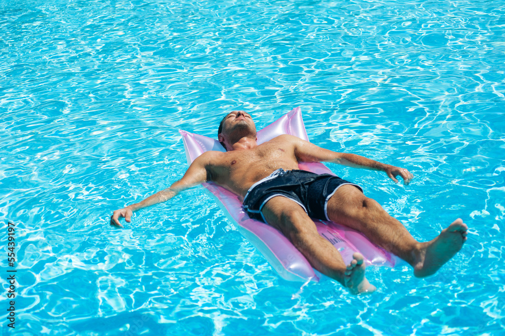 Young man relaxing on swimming pool.