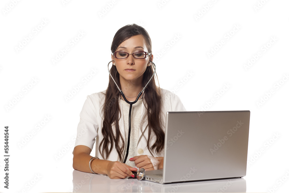 handsome female doctor examines her computer with a stethoscope handsome female doctor examines her computer with a stethoscope