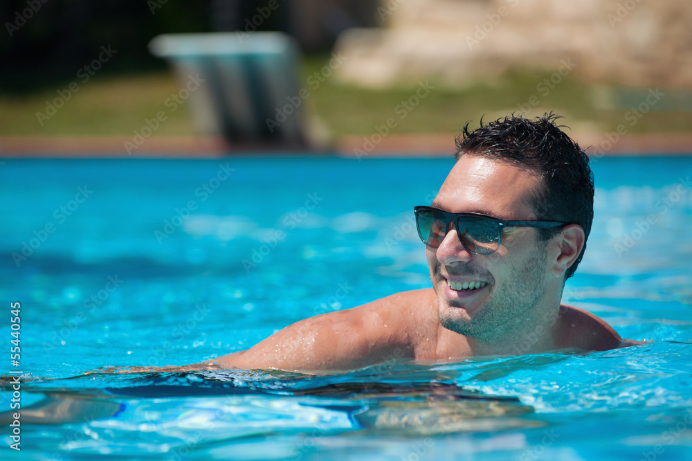 Handsome and happy man portrait in swimming pool.