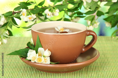 Cup of tea with jasmine, on bamboo mat, on bright background