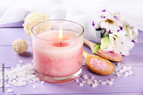 Beautiful pink candle with flowers on purple wooden background