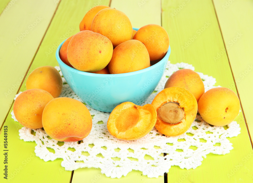 Fresh natural apricot in bowl on green wooden table