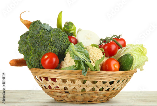 Fresh vegetables in basket on wooden table on white background