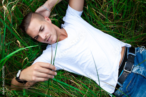 beautiful young man lying on green gras