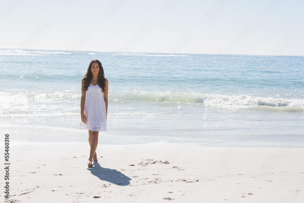 Beautiful brunette in white sun dress walking from the sea Beautiful brunette in white sun dress walking from the sea