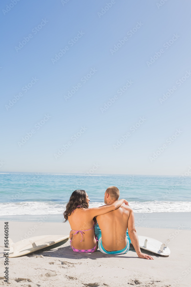Loving young couple sitting with their surfboards