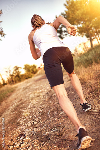 Sporty female jogger running on trail in the park.
