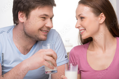 Drinking milk together. Young couple drinking milk and looking a