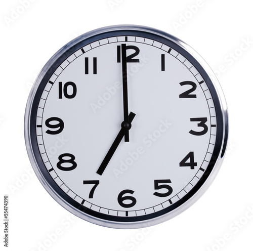 Round office clock shows seven o'clock