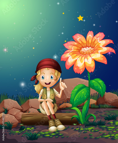A young girl sitting above a log near the giant flower