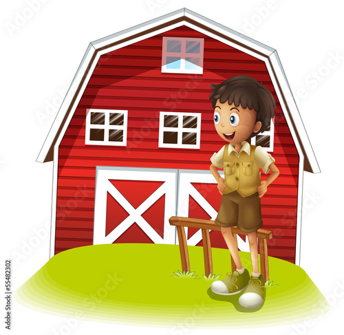 A boy standing in front of the red barnhouse