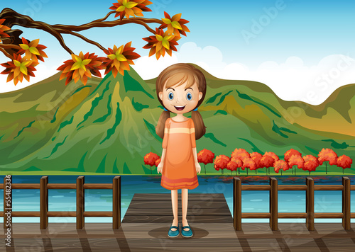 A young girl standing in the middle of the wooden bridge