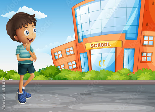 A young boy at the street across the school building