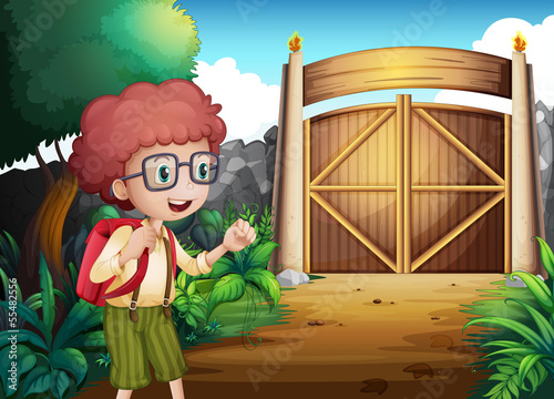 A boy with a red backpack inside the gated yard