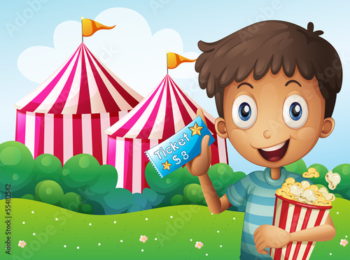 A boy holding a ticket and a pail of popcorn