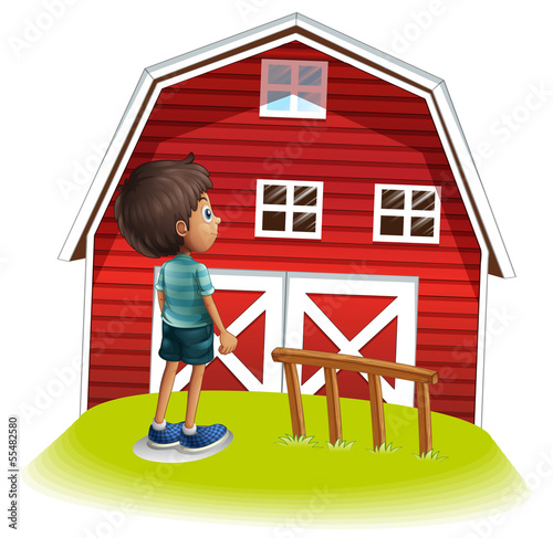 A boy standing in front of the red farmhouse