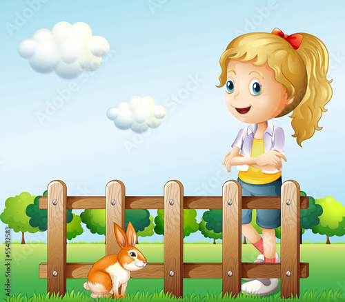 A girl near the fence with a rabbit
