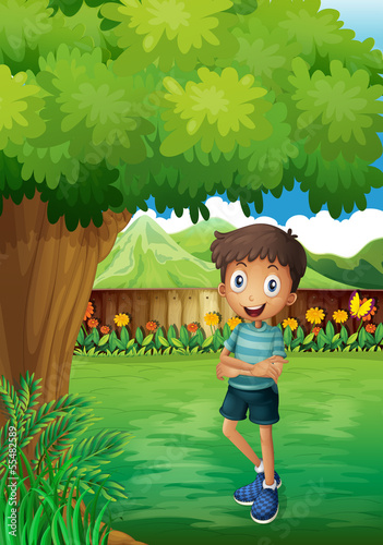 A smiling young man near the tree inside the gated yard