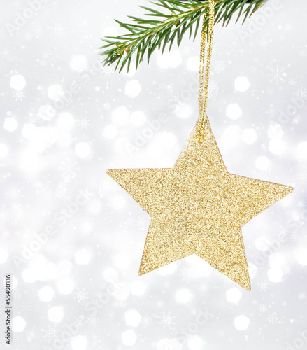 Christmas card with golden star and pine branch on Defocused Chr