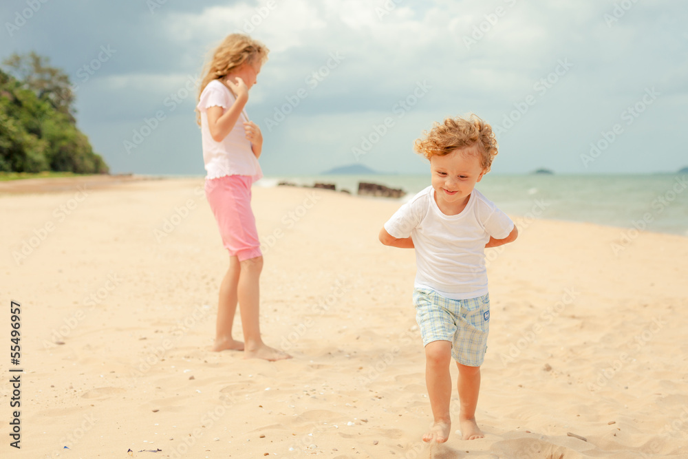 two happy kids playing at the beach in the day time