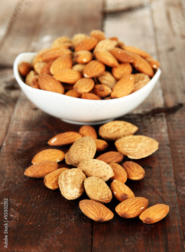 Almond in bowl, on wooden background