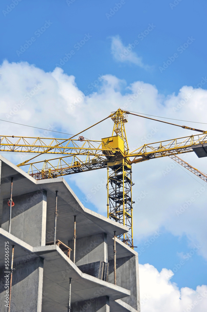 Crane and building construction site against blue sky