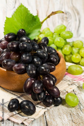 Fresh green and red grapes in a wooden bowl