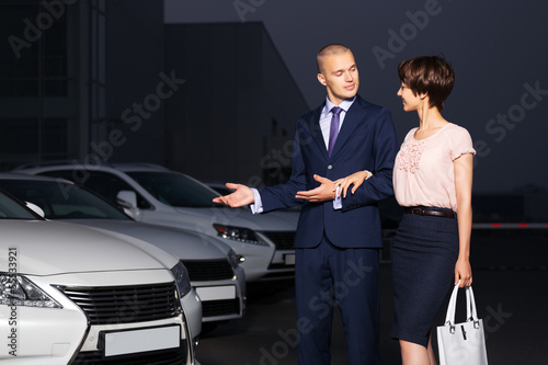 Young couple collecting new car at dealership lot