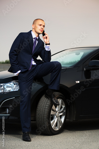 Young businessman calling on the phone at the car © Wrangler