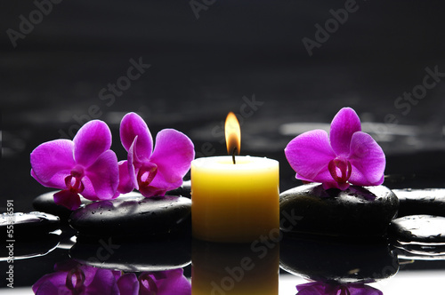 Three red orchid with yellow candle and therapy stones
