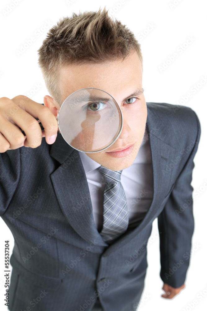 Young businessman looking through magnifying glass isolated Young businessman looking through magnifying glass isolated