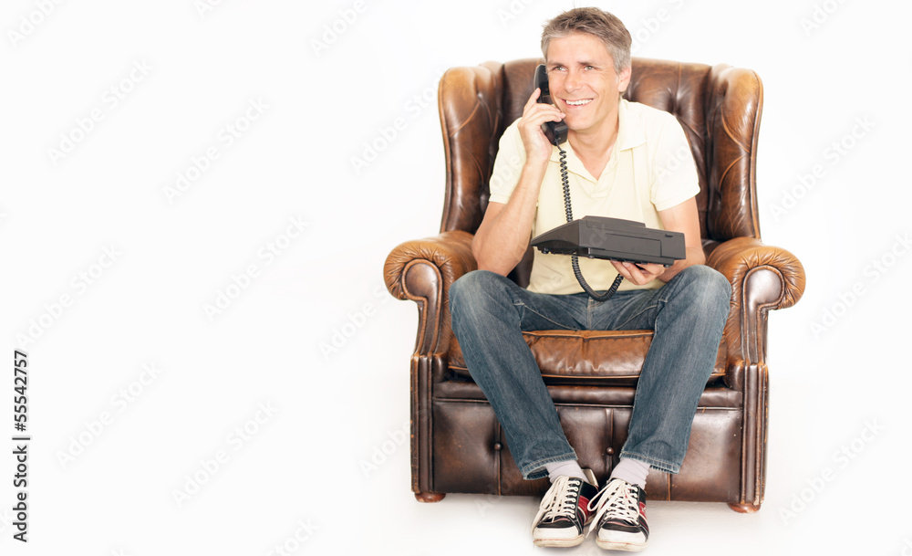 Mann telefoniert auf einem Sessel Mann telefoniert auf einem Sessel