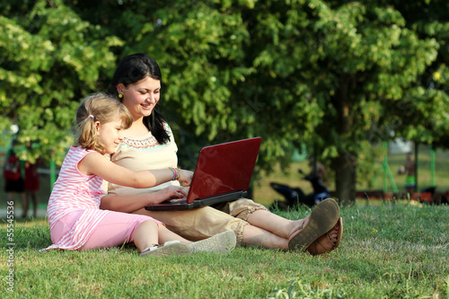 child and girl with laptop in park