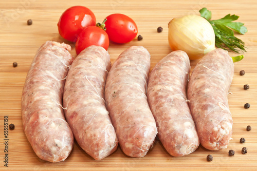Uncooked sausage with vegetables on the chopping board